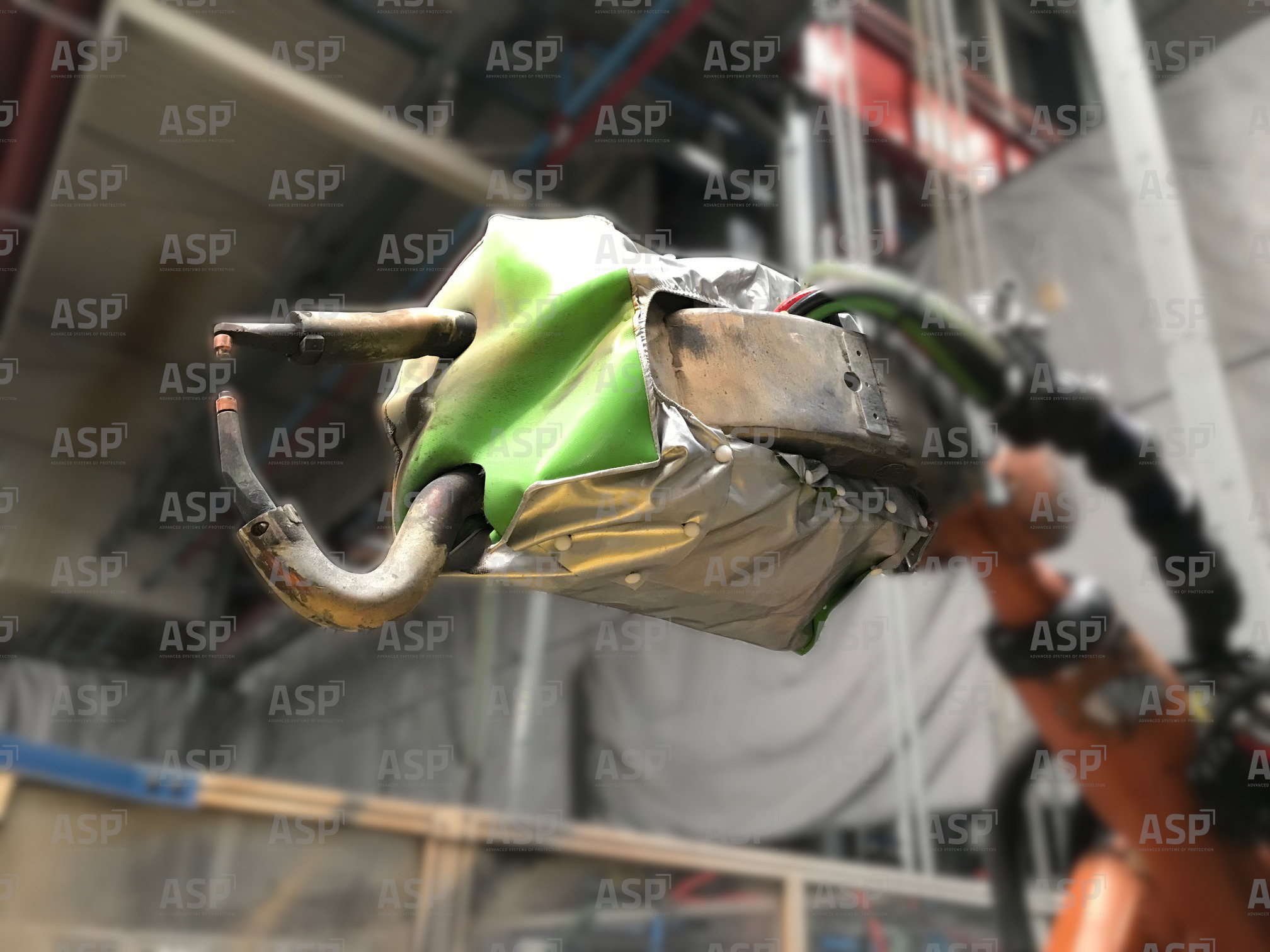 Robot gripper protected by a green cover for welding.